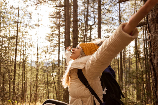 istock Woman with backpack at woods with hands raised 1309408315