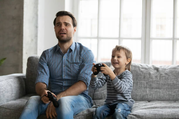 istock Funny upset dad losing video game to little son 1309409450