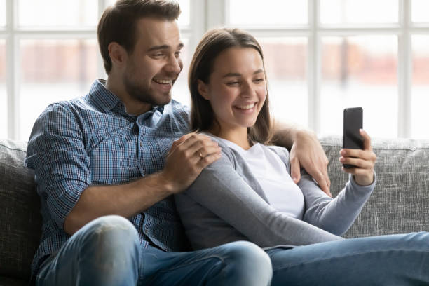 istock Happy millennial husband and wife using mobile phone 1309409488