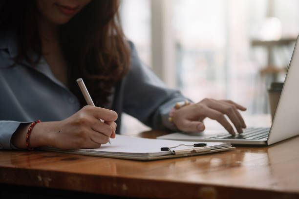 istock Shot of woman making notes while using laptop, working or preparing for business meeting or online study. 1309411564