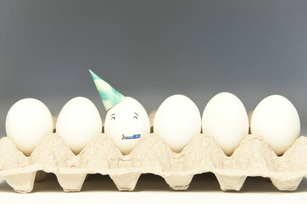 Face wearing a party hat and blowing a party horn, celebrating A face illustrated on an egg shell wearing a party hat and blowing a party horn while celebrating. sabby stock pictures, royalty-free photos & images