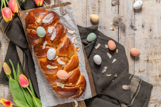 istock Portuguese traditional Easter cake. Folar with eggs on easter table. Blossom tulips, colorful painted eggs and feathers 1309411940
