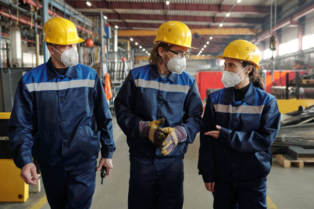 istock Group of workers or engineers in protective workwear and respirators moving along workshop 1309413049