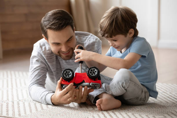 feche o filho pequeno consertando cartão de brinquedo com o pai amoroso - close up truck pick up truck gear - fotografias e filmes do acervo