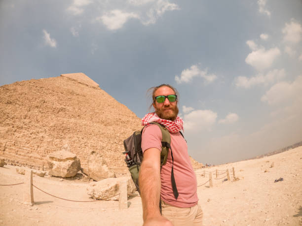 istock Man takes selfie at the pyramids in Egypt, he uses an action camera 1309416395