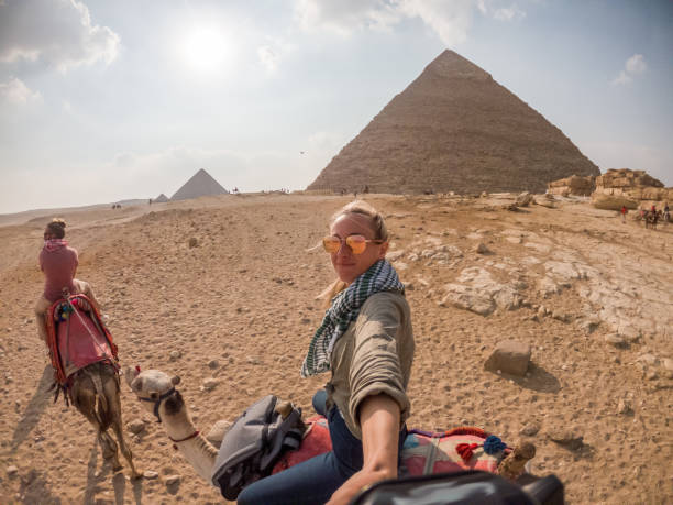 istock Couple take selfie while riding camels, pyramids in background 1309416461