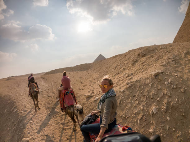 istock Couple take selfie while riding camels, pyramids in background 1309416521