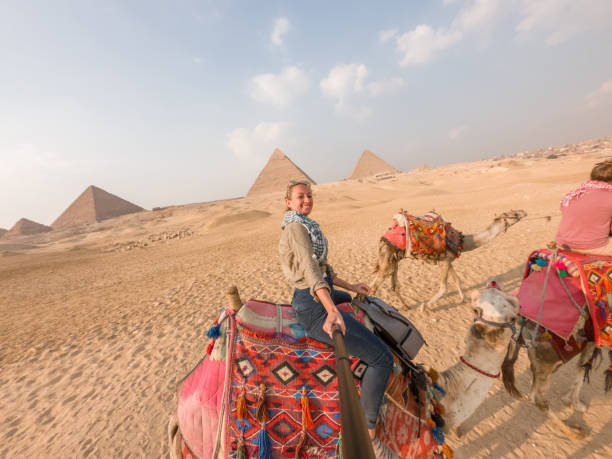 istock Couple take selfie while riding camels, pyramids in background 1309416534