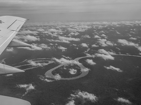 View from airplane window. Wing of an airplane flying above the clouds over Amazon River. Top View of Amazon rainforest. Peru, Brazil. Colombia.