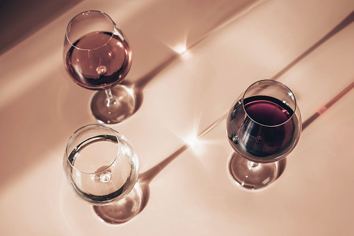 Glasses of red, rose and white wine with sunshine shadow effect. Concept of wine tasting. Flat lay, top view.