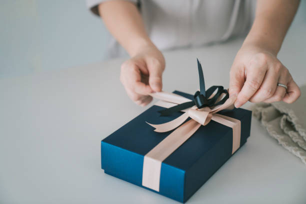 asian chinese mid adult woman receiving and opening gift at kitchen counter - hand wrap imagens e fotografias de stock