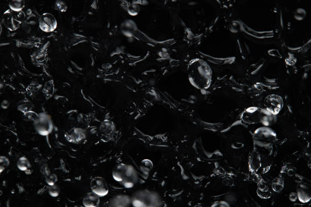 istock Splashes and drops on the surface of the liquid. Abstract Black Background Liquid Texture 1309431182
