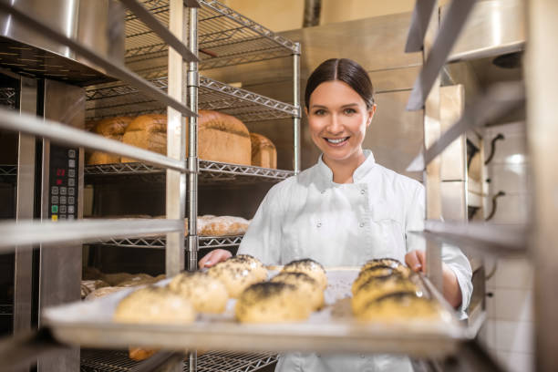 istock Happy woman putting baking sheet with buns on rack 1309431270