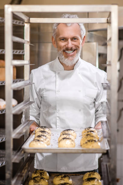 istock Man putting tray of rolls in special rack 1309431407