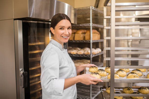 istock Friendly woman putting baking sheet of buns on rack 1309431408
