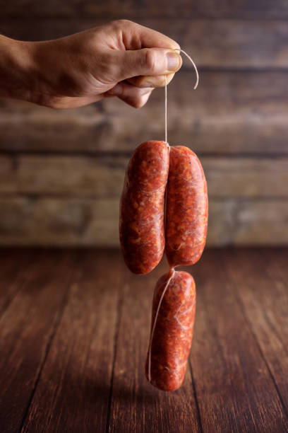 istock Hand holding Italian Raw sausage chain hanging 1309439488