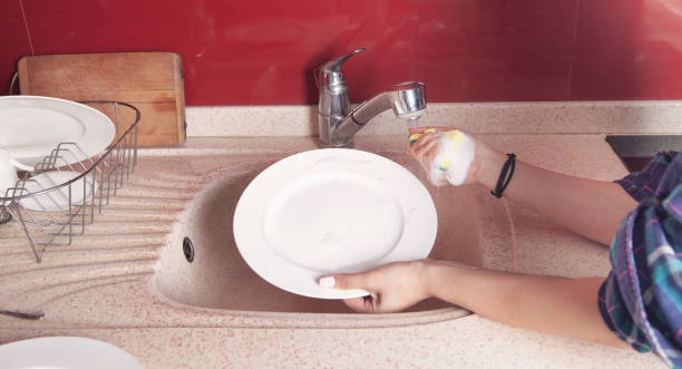 istock Woman hands washing white plate in kitchen sink. 1309440396