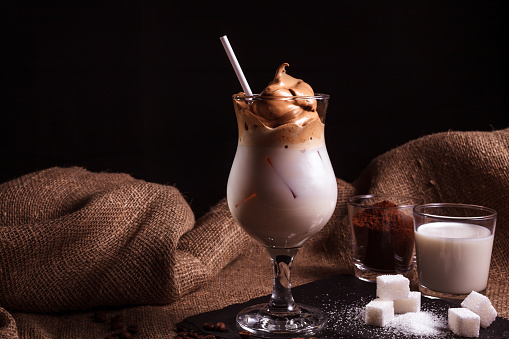 Cold trendy drink Korean dalgon iced coffee on dark background. delicious and popular coffee in the trend