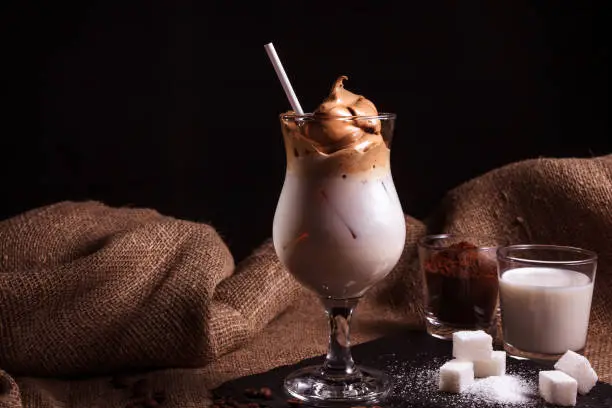 Photo of Cold trendy drink Korean dalgon iced coffee on a dark background. delicious and popular coffee in the trend