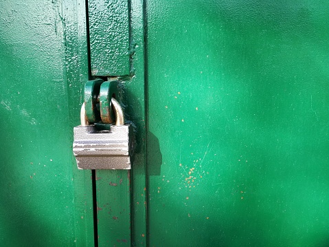 Closeup of metal clock with green painted door in the background