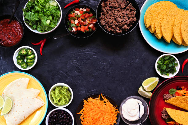 istock Taco bar frame with assorted ingredients on a dark slate background 1309441980