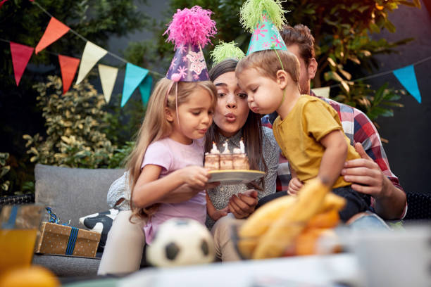 gathered young family blowing birthday candles together. birthday, togetherness concept gathered young family blowing birthday candles together. birthday, togetherness happy birthday cousin stock pictures, royalty-free photos & images
