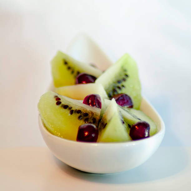 still life picture present a white spoonful of chopped green kiwi and some redpomegranate arils