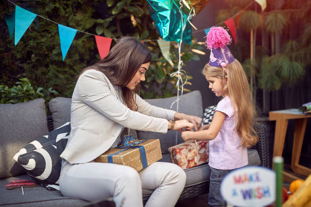 young female brunette opening  birthday presents with sweet little girl. birthday , leisure, concept young female brunette opening  birthday presents with sweet little girl. birthday , leisure happy birthday cousin stock pictures, royalty-free photos & images