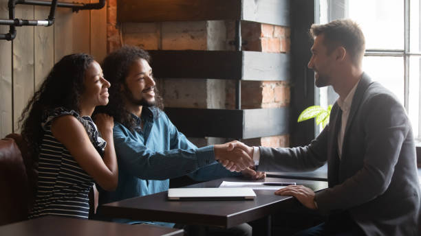 clientes felices y agente de seguros apretando a mano al reunirse en el café - couple young adult african descent multi ethnic group fotografías e imágenes de stock