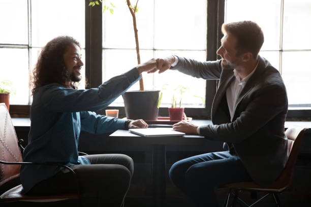 istock Two diverse men friends bumping fists above table at coffeehouse 1309449037