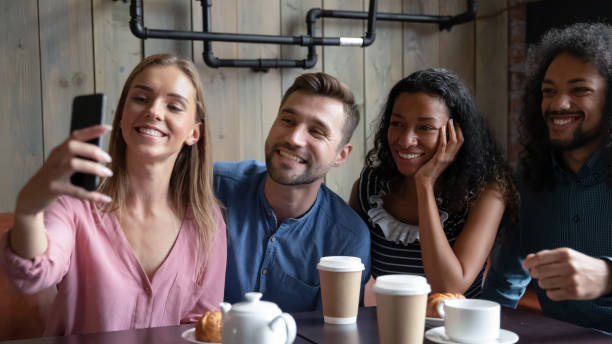 istock Joyful diverse mates company posing for group selfie at cafe 1309449055