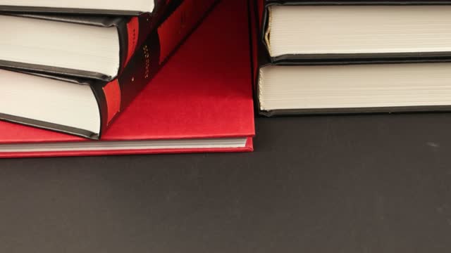 Books in red and black bindings on a dark table