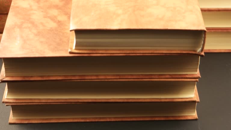 Books in a pale brown bindings on dark table