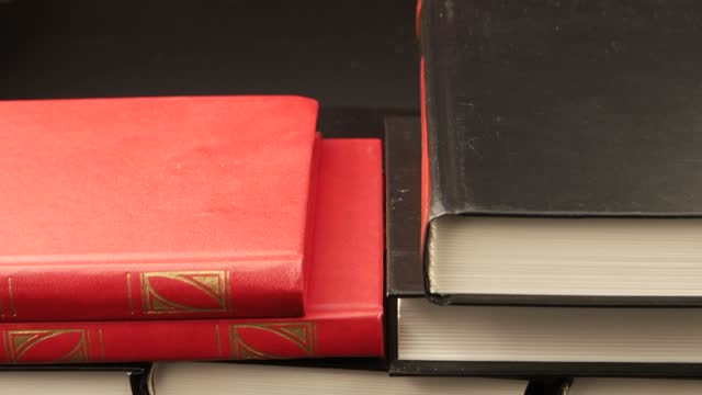 Books in red and black bindings on a dark table
