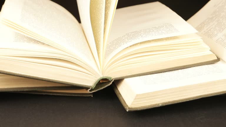 Open books in different bindings  on a dark table