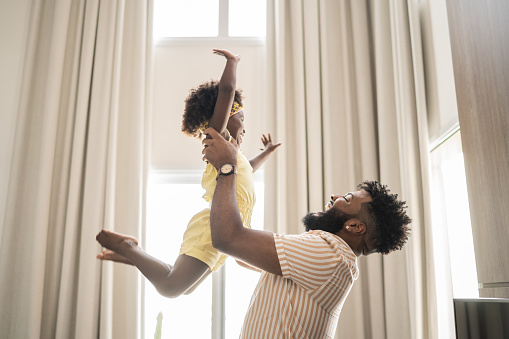 Father holding daughter up in the air at home