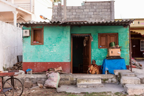 Mysuru, Karnataka, India - January 2019: An Indian woman sitting outside her rustic hut on the streets of Chamundi Hills.
