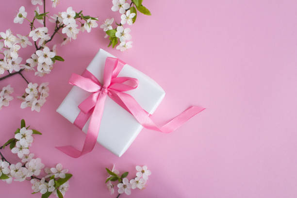 istock Gift with pink  bow and flowering tree branches on the pink background.Top view.Copy space. 1309452768