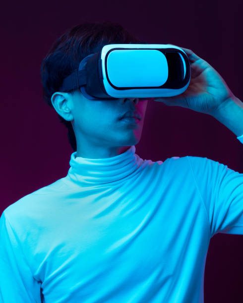 istock Young asian man wearing virtual reality goggles watching 360 degree video in neon light, Technology concept 1309459197