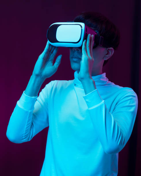 istock Young asian man wearing virtual reality goggles watching 360 degree video in neon light, Technology concept 1309459200
