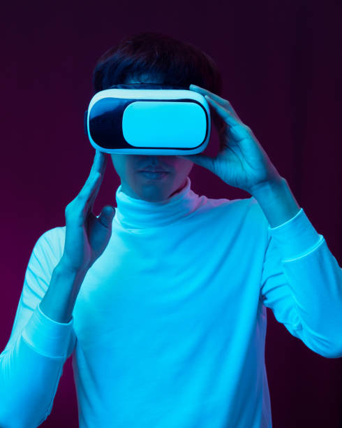 istock Young asian man wearing virtual reality goggles watching 360 degree video in neon light, Technology concept 1309459214