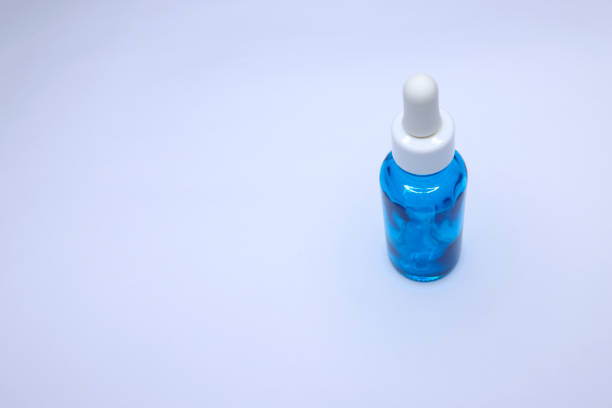 piccola bottiglia a goccia blu vuota su sfondo bianco, contagocce in vetro utilizzato nell'industria cosmetica e farmaceutica - herbal medicine flash foto e immagini stock