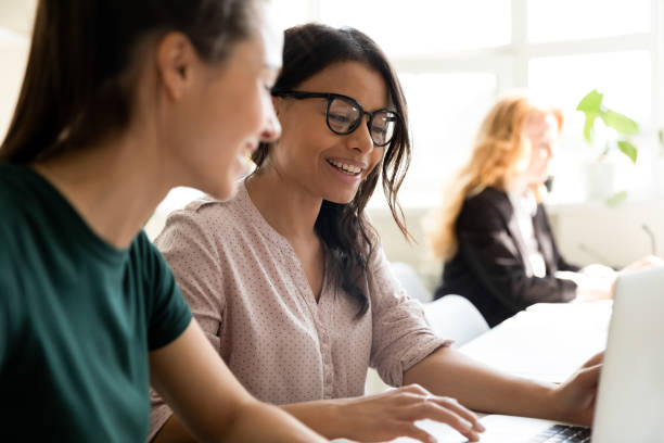 istock Smiling multiethnic female colleagues using laptop working on project together 1309460411