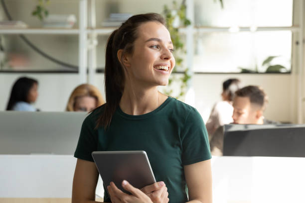 istock Happy female employee standing with digital tablet smiling looking aside 1309460421