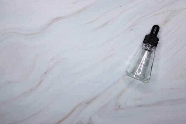 istock Empty small transparent drip bottle on a white-gray marble background, Glass dropper used in the cosmetics and pharmaceutical industry 1309460647