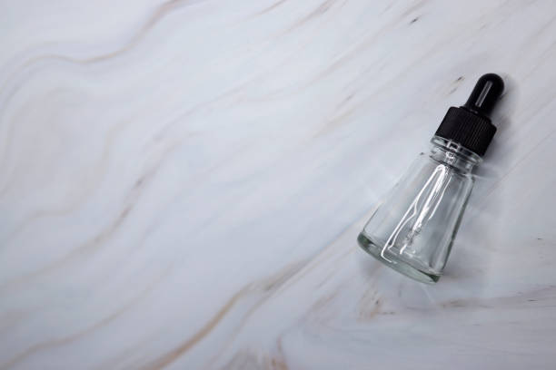 istock Empty small transparent drip bottle on a white-gray marble background, Glass dropper used in the cosmetics and pharmaceutical industry, Close-up 1309461263