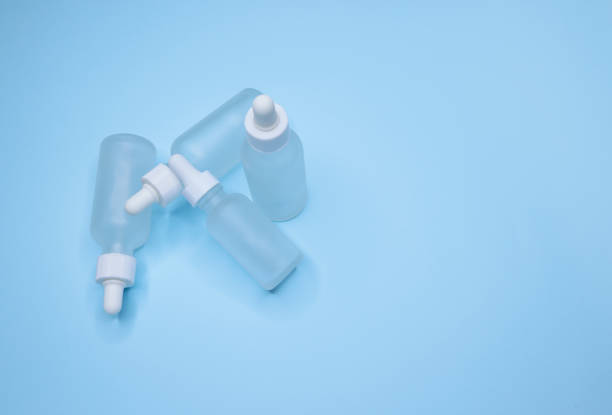 istock Four empty small matte white drop bottles on a blue background, Glass dropper used in the cosmetics and pharmaceutical industry 1309461395