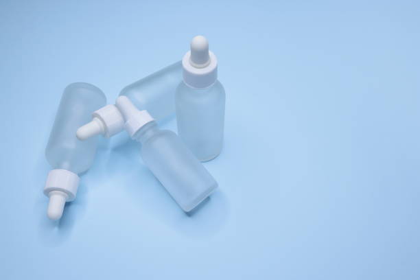 istock Four empty small matte white drop bottles on a blue background, Glass dropper used in the cosmetics and pharmaceutical industry, Close-up 1309461438