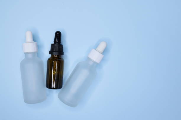 istock Three empty small brown and white drip bottles on a blue background, Glass dropper used in the cosmetics and pharmaceutical industry 1309461833