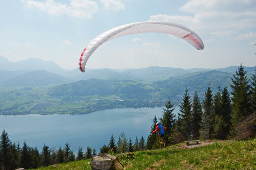 A paraglider starting and flying from the Grünberg near Gmunden over the lake Traunsee, Austria, Europe